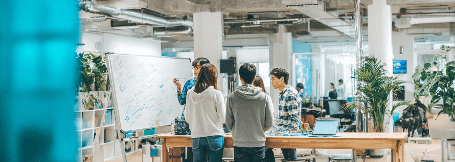 Modern co-working space with a small team collaborating at a whiteboard